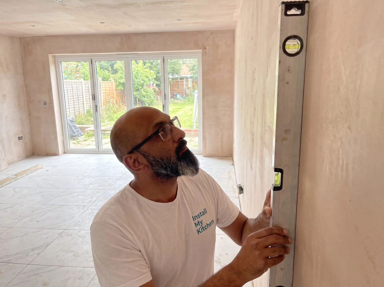 Kitchen fitter checking a spirit level's accuracy against a wall before starting work