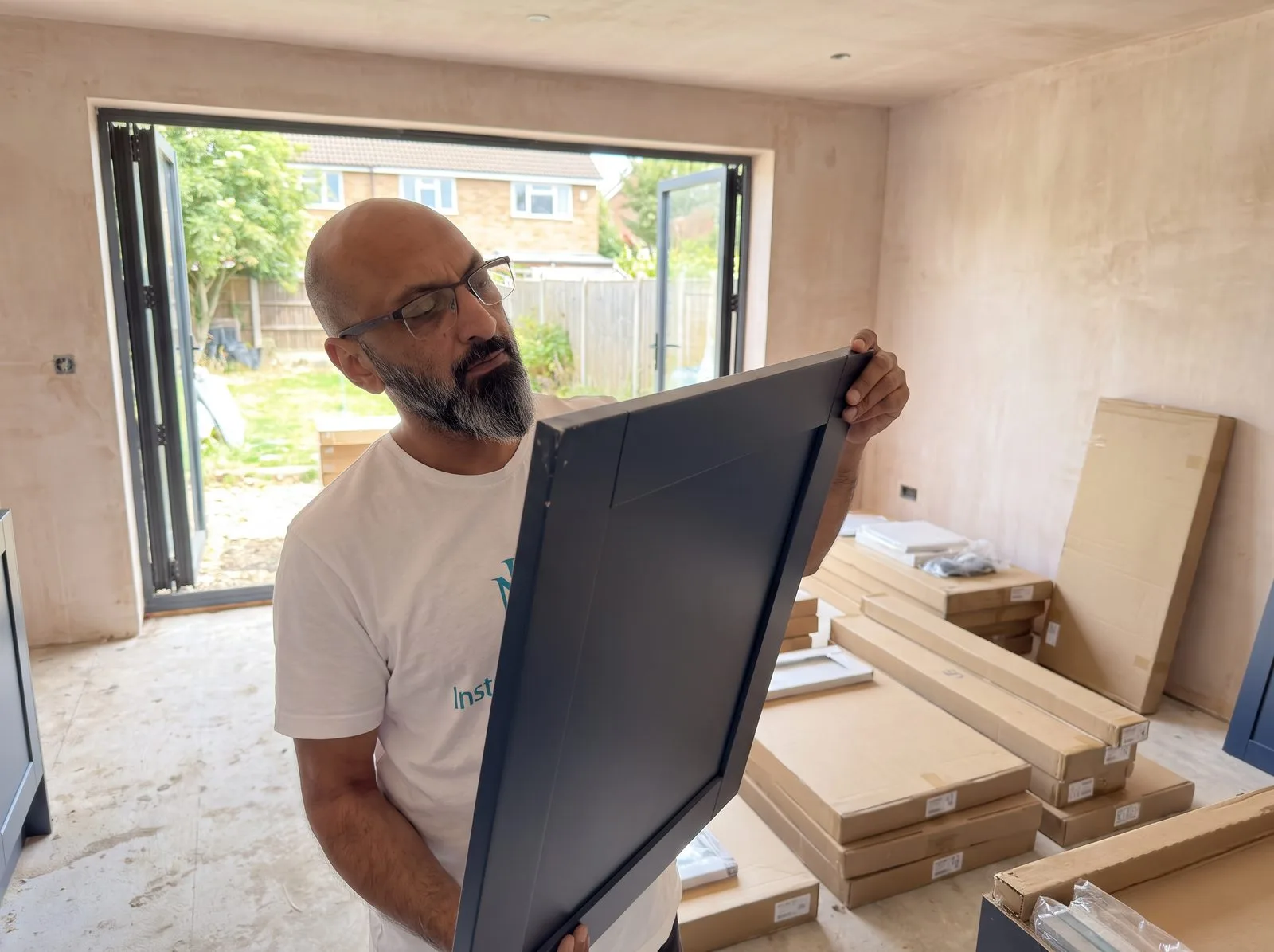 Kitchen fitter inspecting a cabinet door for damage against flat-pack boxes