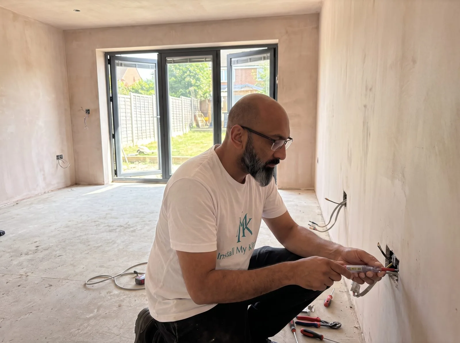 Kitchen fitter proving a socket is safely isolated with a voltage tester before strip-out