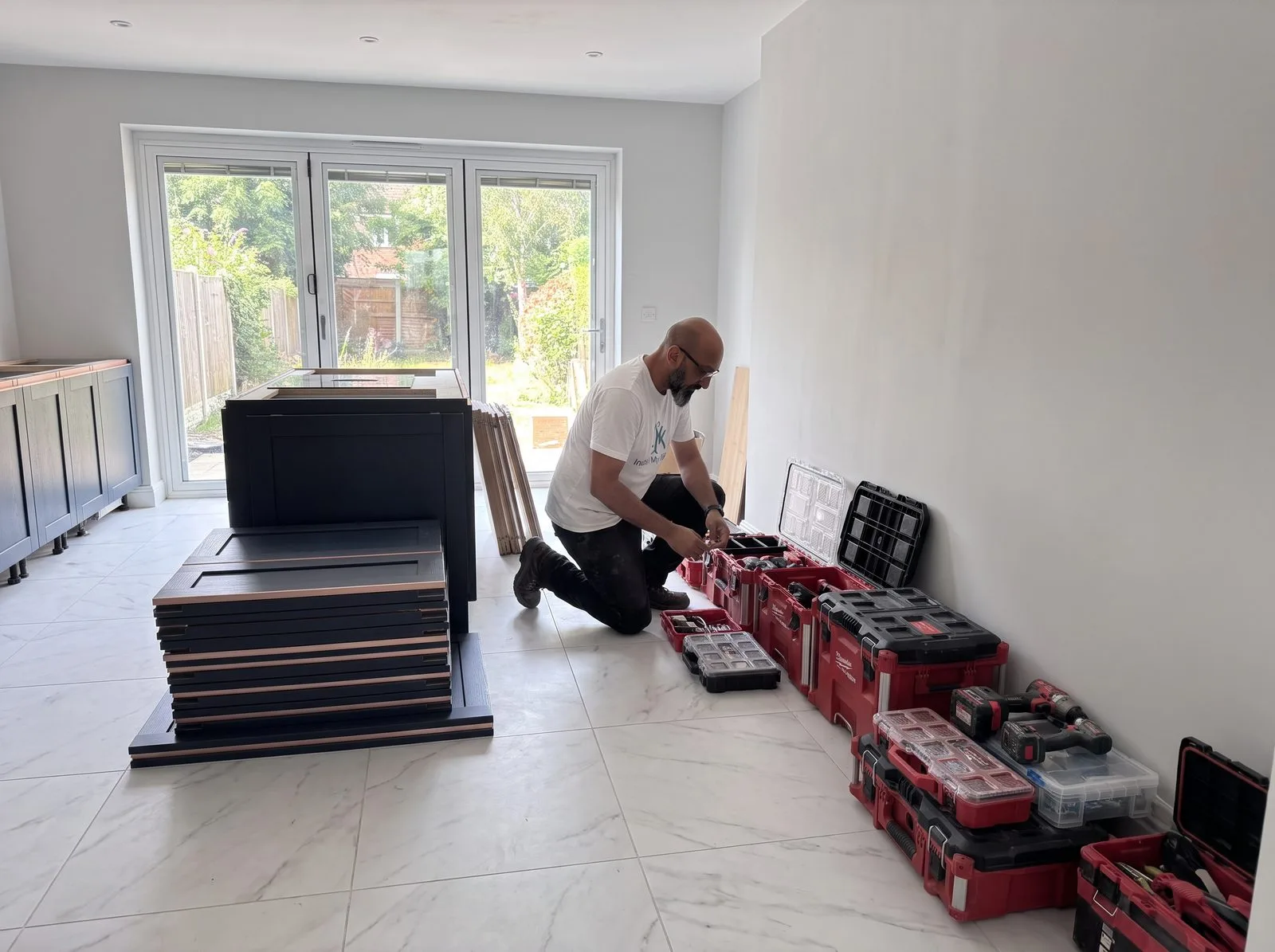 Kitchen fitter organising toolboxes and unpacking cabinets on carcass installation day