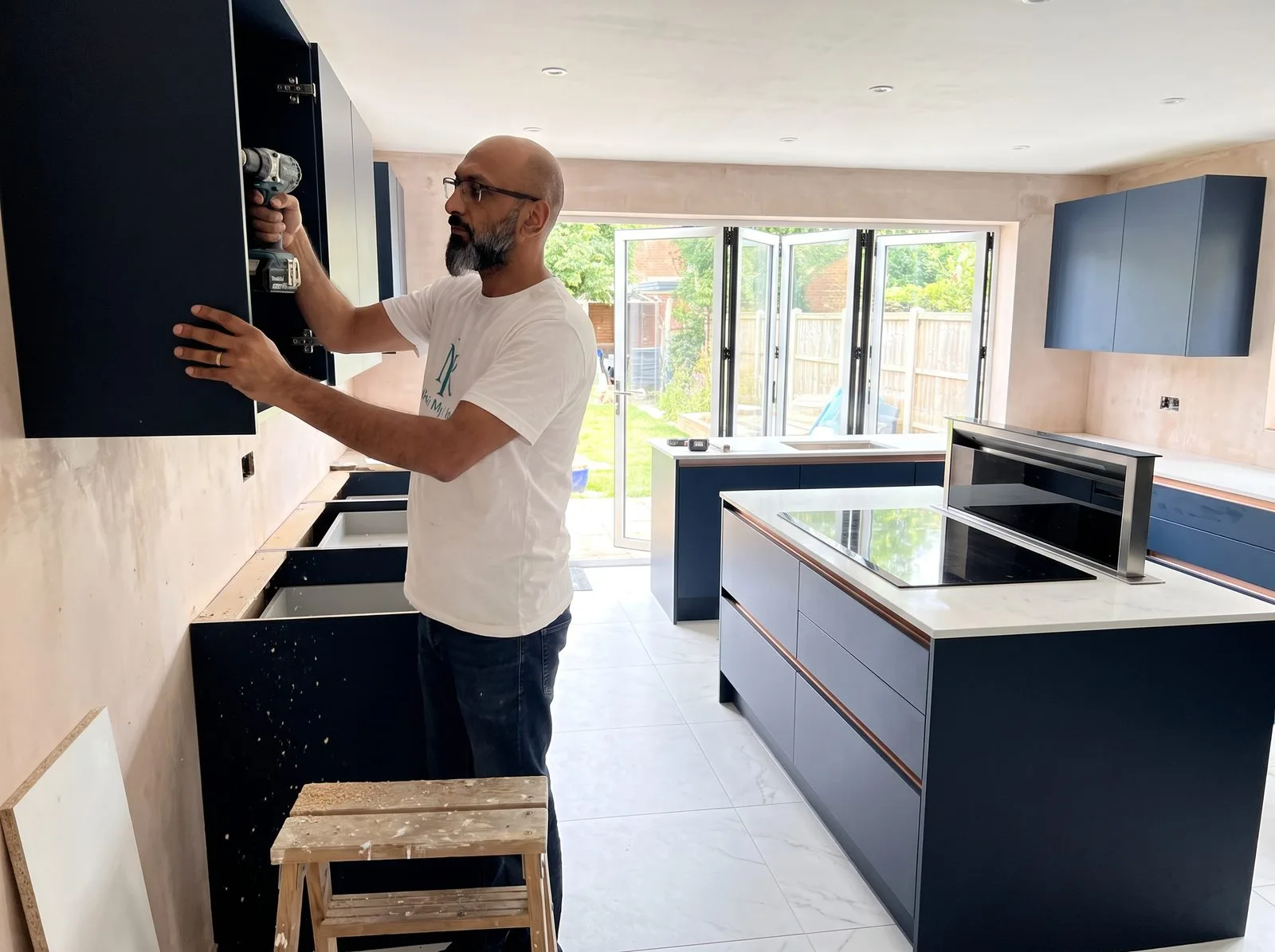 Kitchen fitter fixing a dark blue wall cabinet bracket to a stud wall