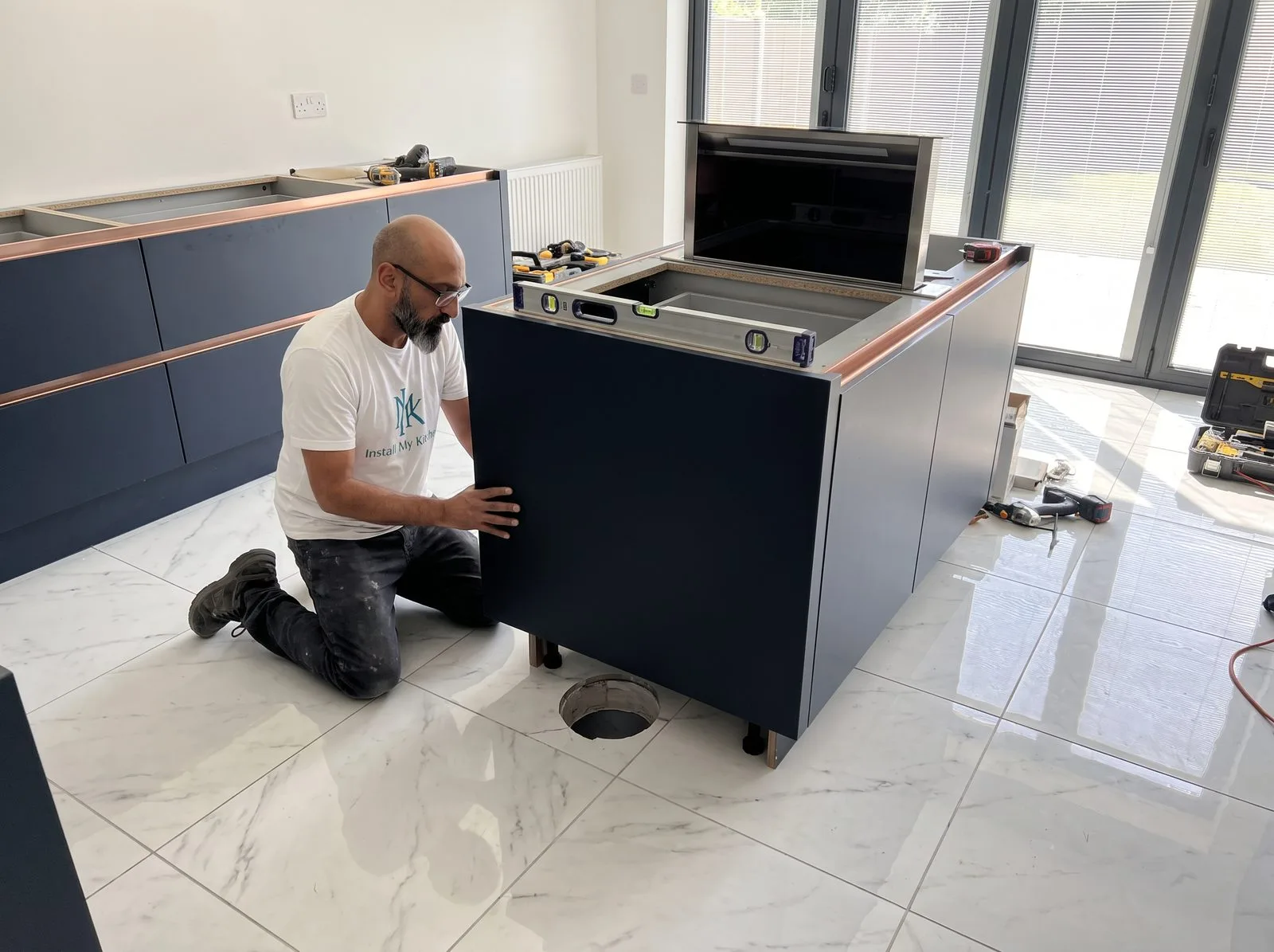 Kitchen fitter positioning an island cabinet carcass over a floor duct cut-out