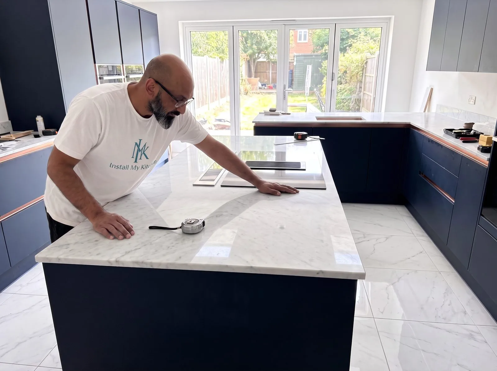 Kitchen fitter checking a seam joint on a white quartz island worktop