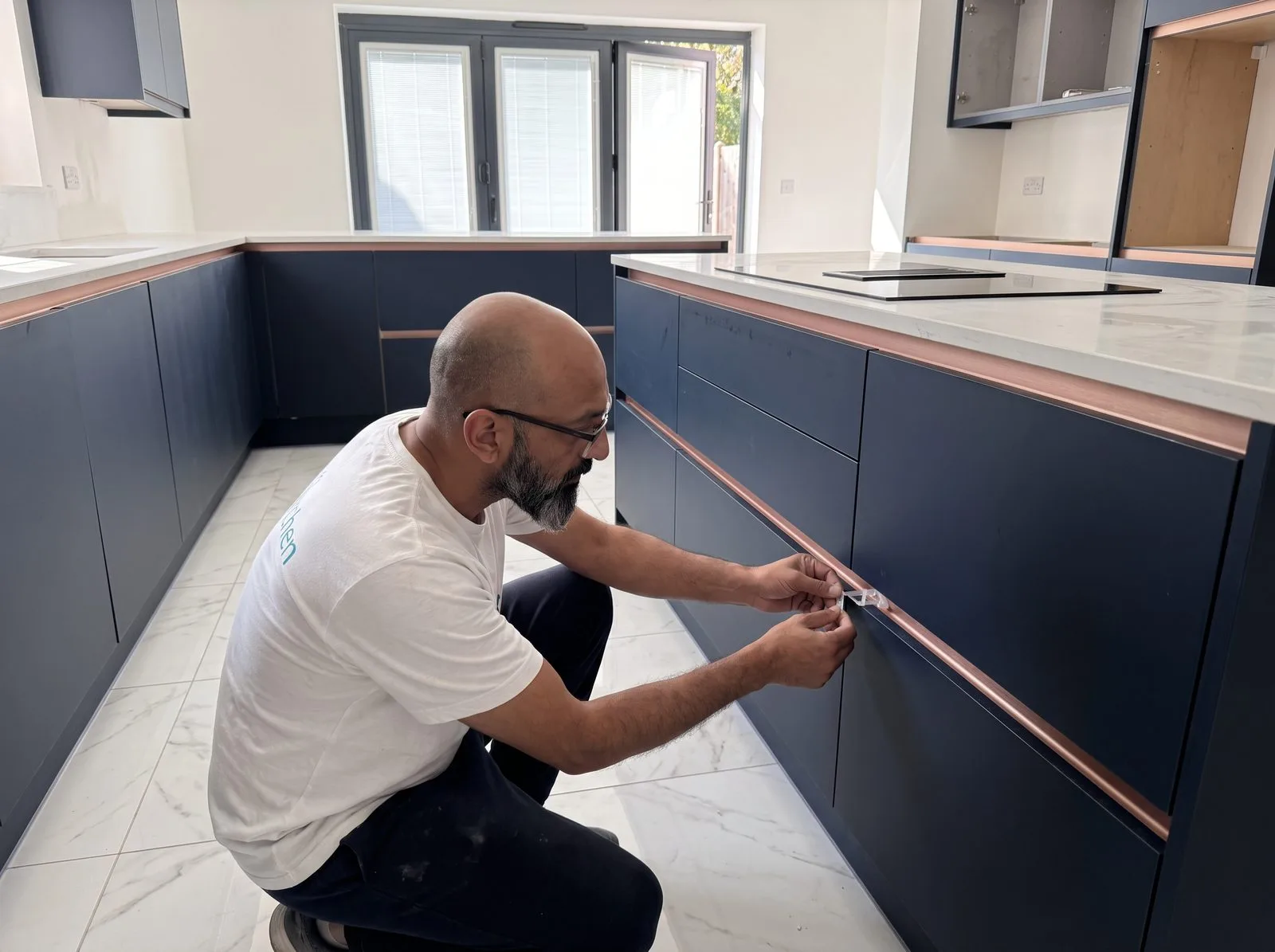 Kitchen fitter checking a cabinet door gap with a spacer tool during snagging