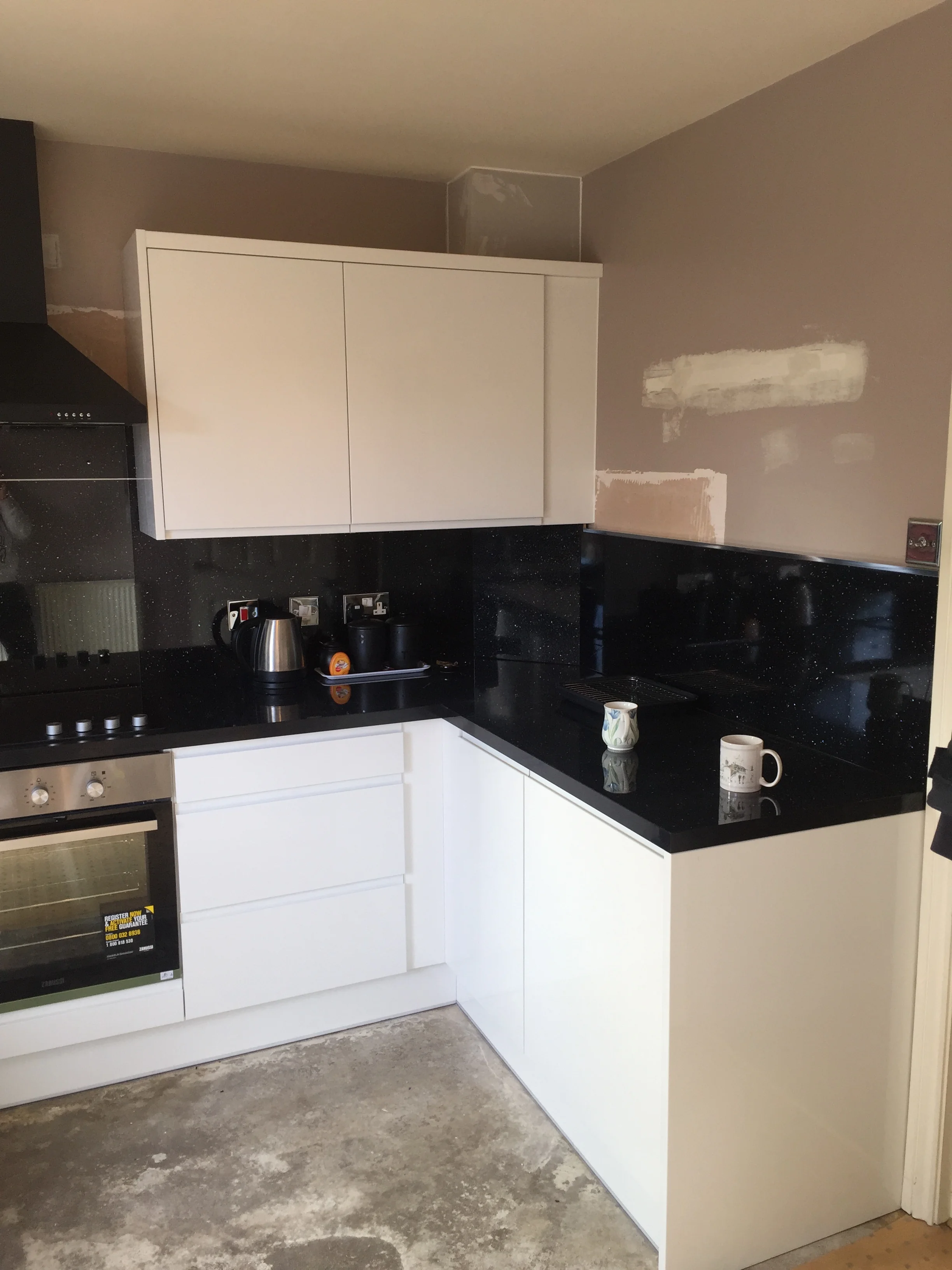 Kitchen fitter Solihull — white handleless kitchen with black granite worktop installed in Solihull B91