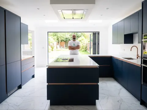 Pindi Sahota standing in a finished navy blue kitchen installation
